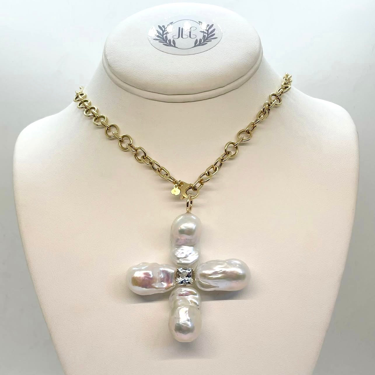 Pearl pendant on a mannequin bust with gold chain necklace.