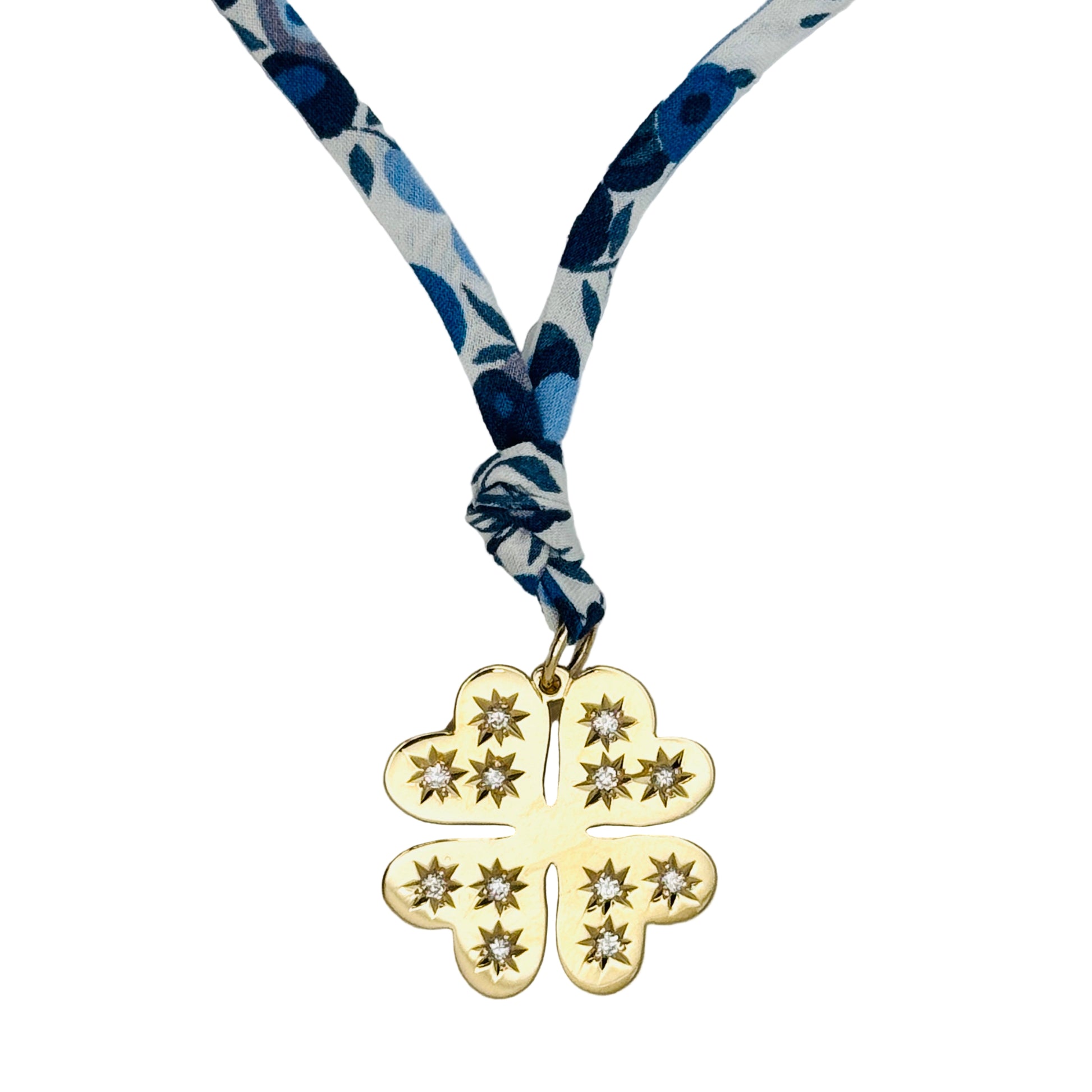 Gold four-leaf clover pendant on a blue and white floral ribbon against a white background