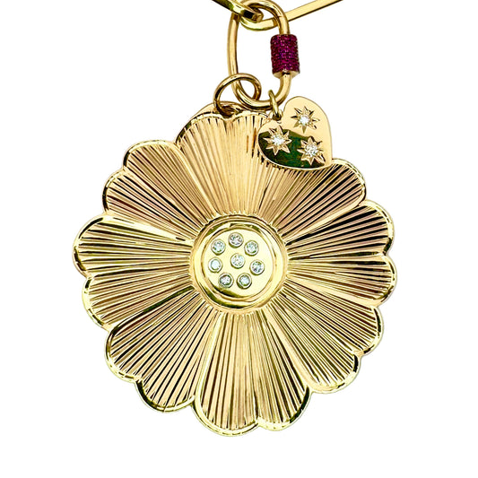 Gold flower-shaped keychain with gemstone center on a white background