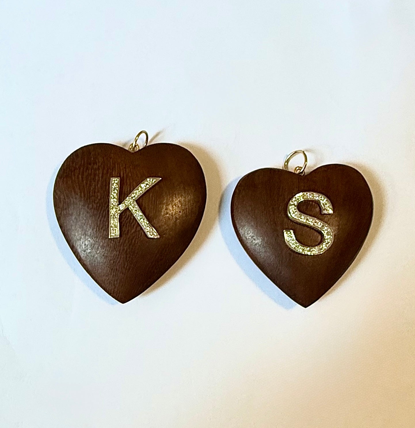 Two heart-shaped pendants with 'K' and 'S' on a light background