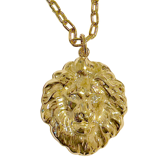 Gold lion head pendant on a chain against a white background