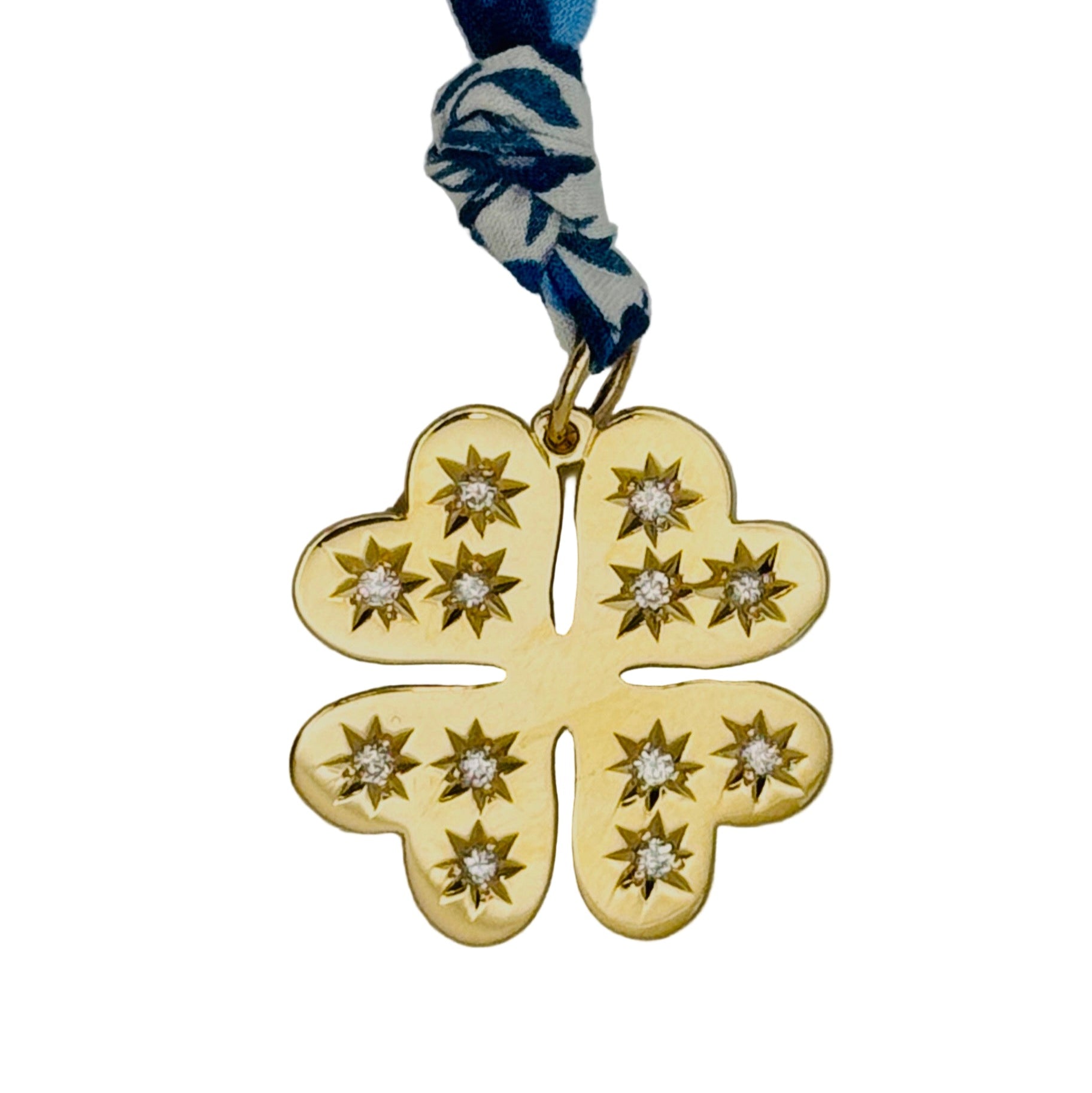 Gold four-leaf clover pendant with star designs on a blue and white patterned cord against a white background