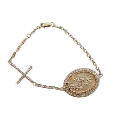 A gold-tone bracelet featuring a round charm with either a Madonna or St. Christopher figure, accompanied by a diamond-frame design and a cross charm.