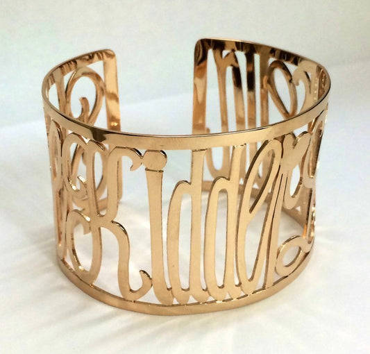 A 14k gold yellow gold cuff bracelet with customizable engraving, showcasing three names.