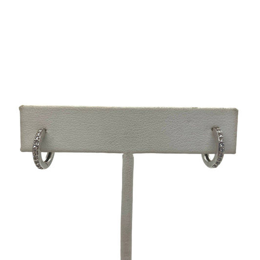 A pair of 14k white gold huggy earrings with pave diamonds displayed on a mannequin bust.