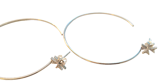 A pair of silver-colored hoop earrings with a Maltese cross design and small star-shaped embellishments.