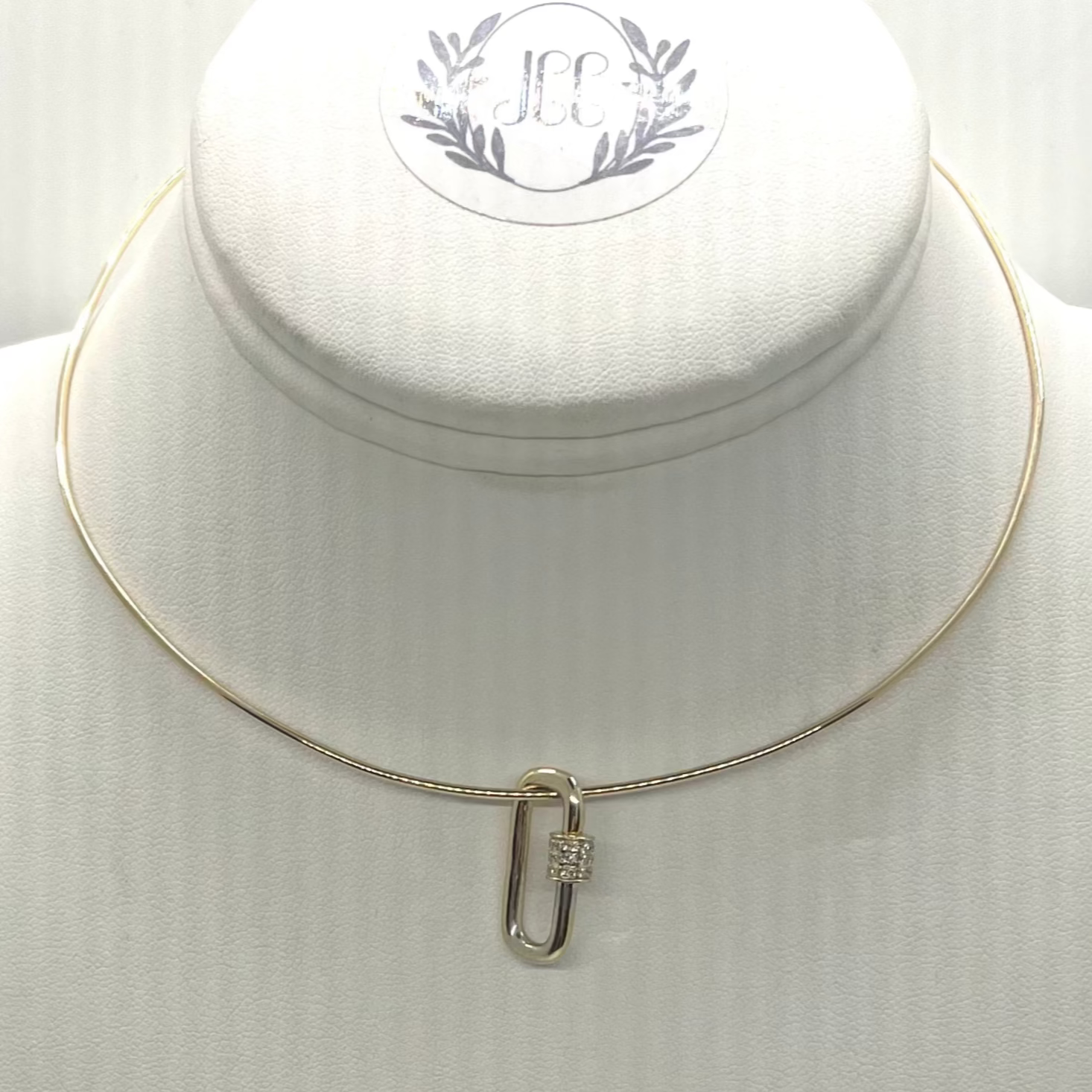 A yellow gold clip with a pave diamond closure displayed on a white mannequin necklace.