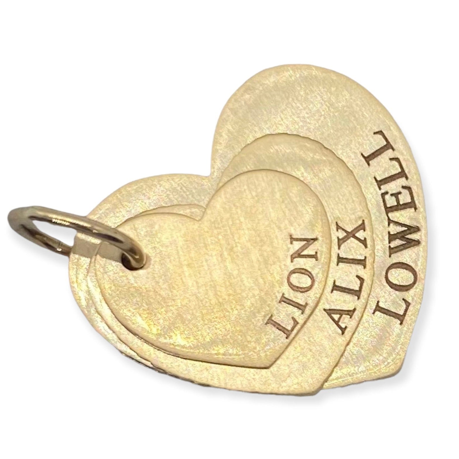 Three gold heart-shaped name stacking pendants with the names LION, ALIX, and LOWELL engraved on them.