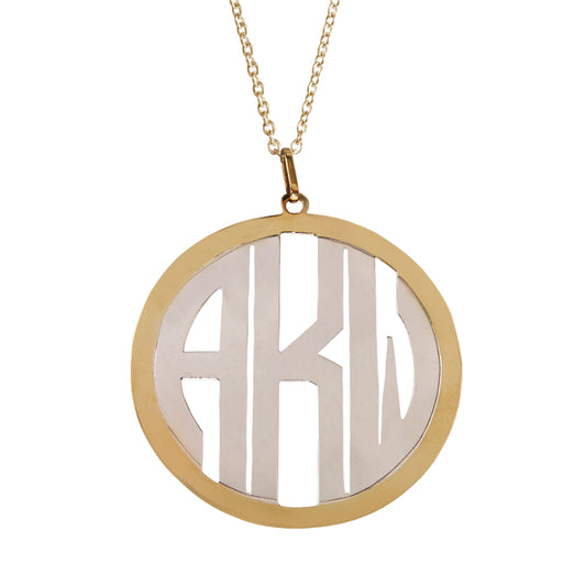 A 14kt yellow gold frame with a 14kt white gold monogram 2” pendant with block lettering.