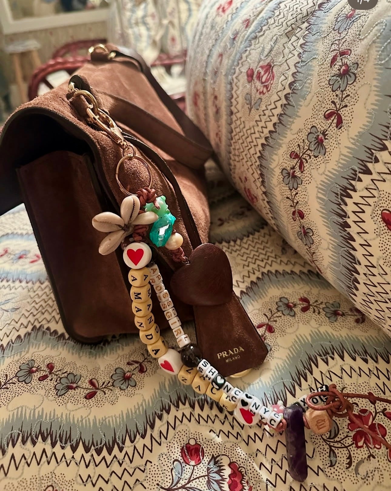 Brown Prada handbag with decorative keychain on a patterned fabric surface