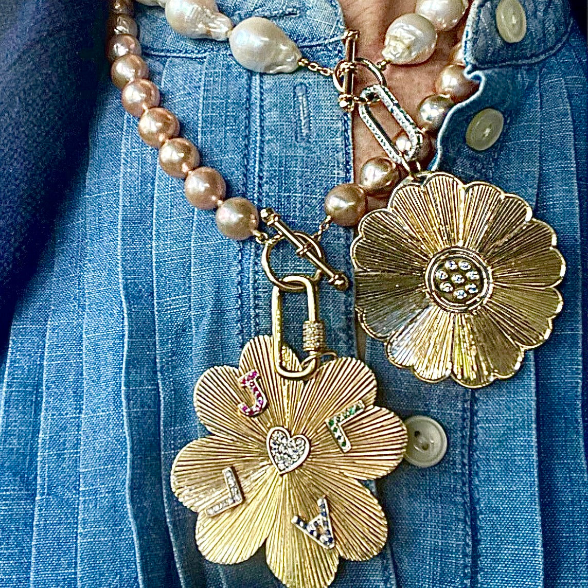 Close-up of a necklace with floral pendants and pearls on a blue denim background