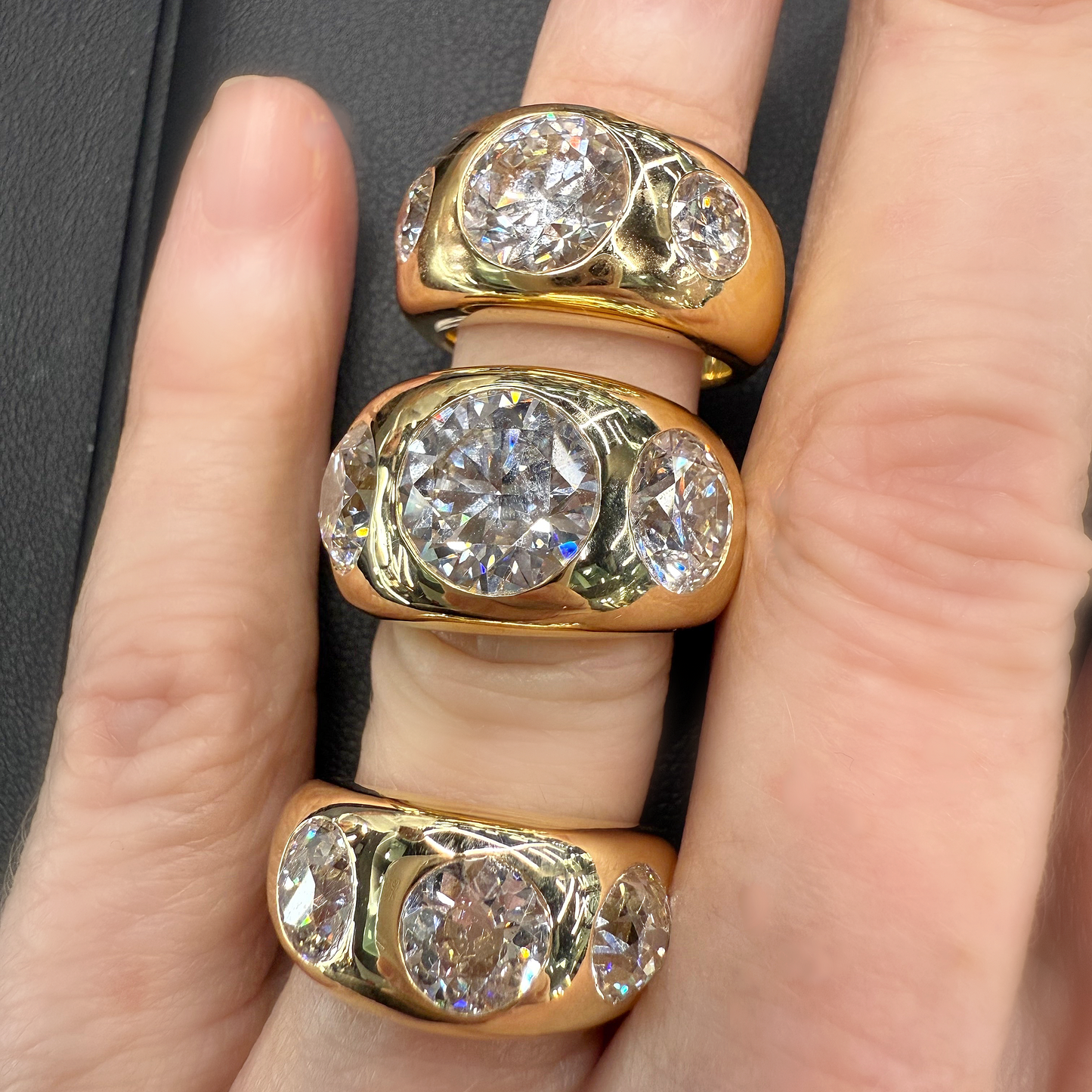 Three gold rings with diamond stones on a finger