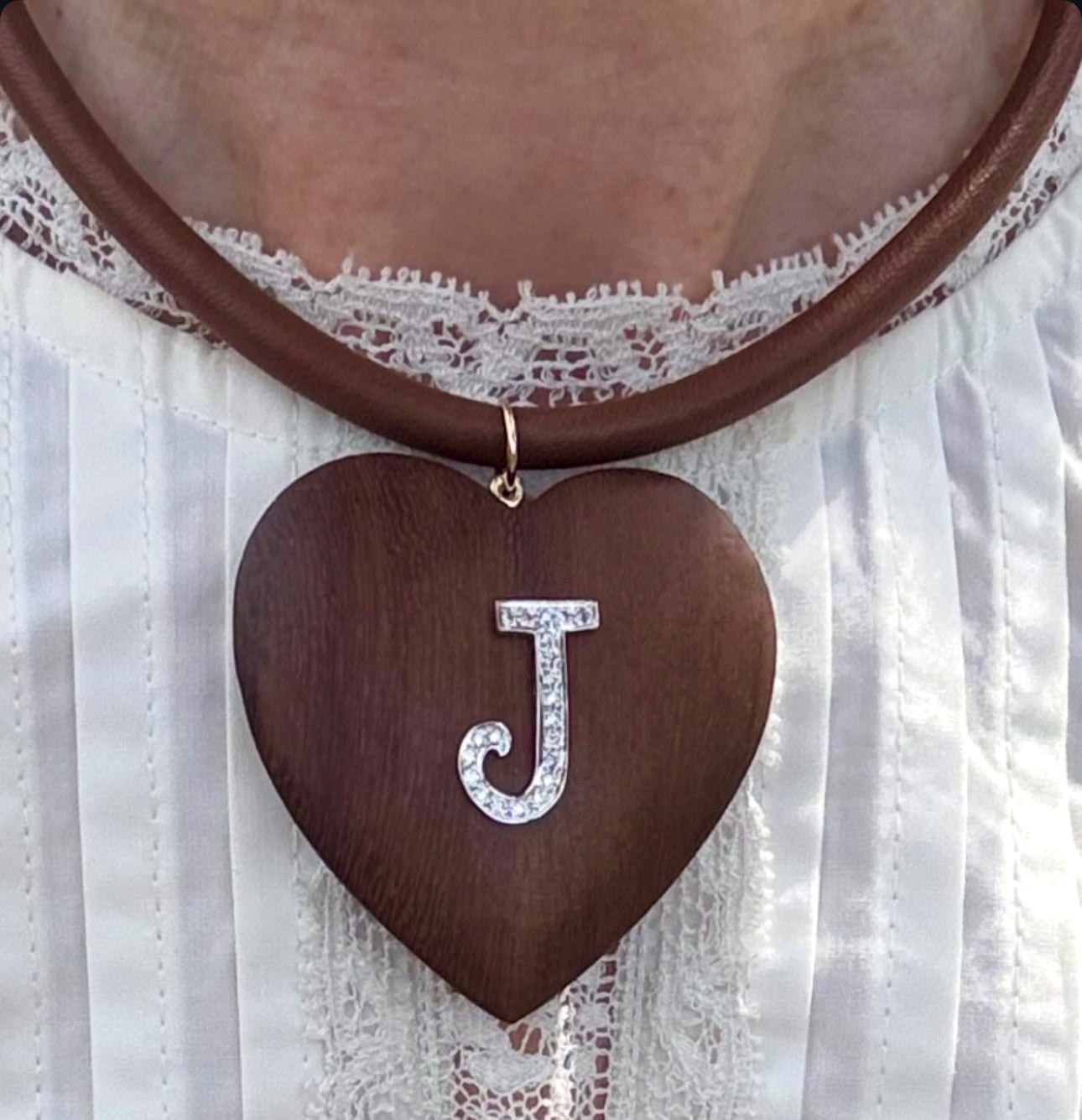 Necklace with a heart-shaped pendant and letter 'J' on a white lace background