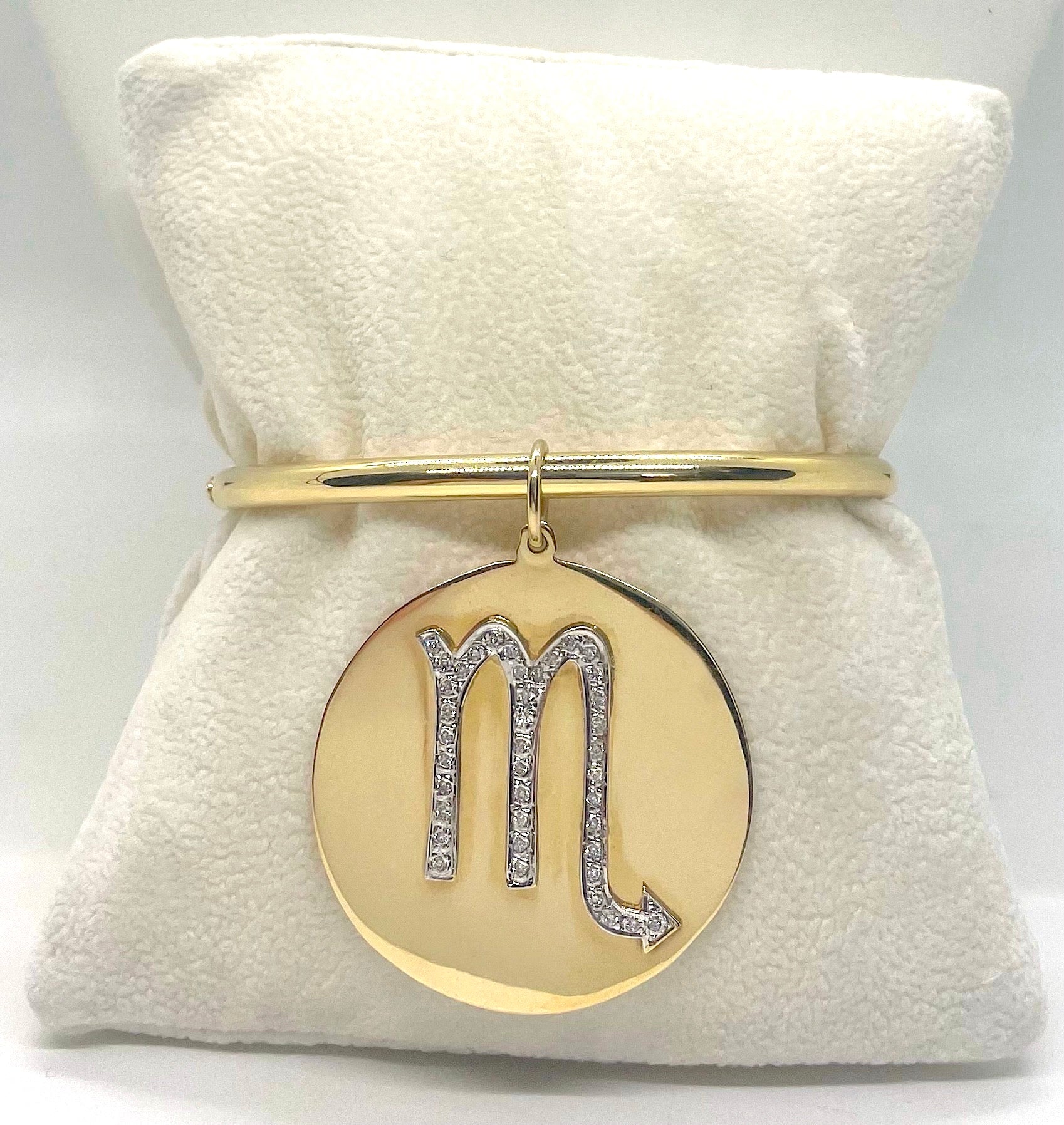 Gold bracelet with a 'Scorpio' symbol pendant on a white background.