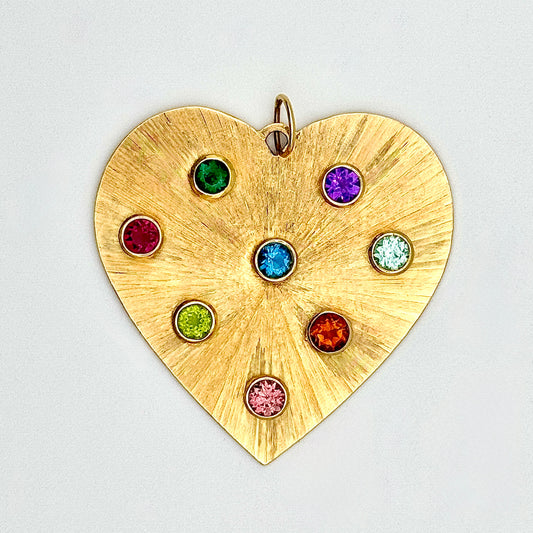 Gold heart-shaped pendant with colorful gemstones on a light gray background