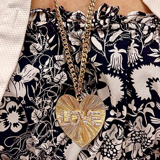 Gold necklace with a heart pendant on a floral-patterned fabric background