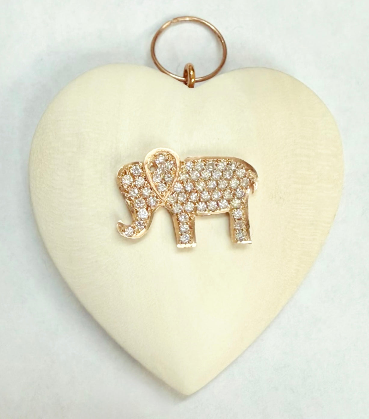 Heart-shaped object with a gold elephant pendant on a white background