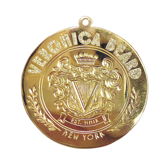 Round gold pendant with ' Veronica Beard' branding and crest on a white background. 