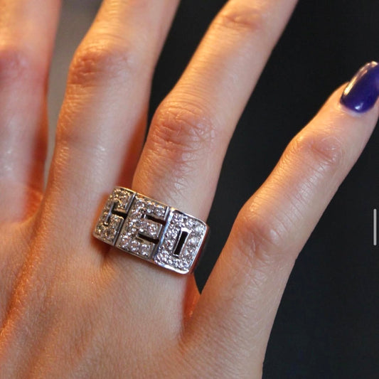 Silver ring with 'CEO' on a hand against a black background