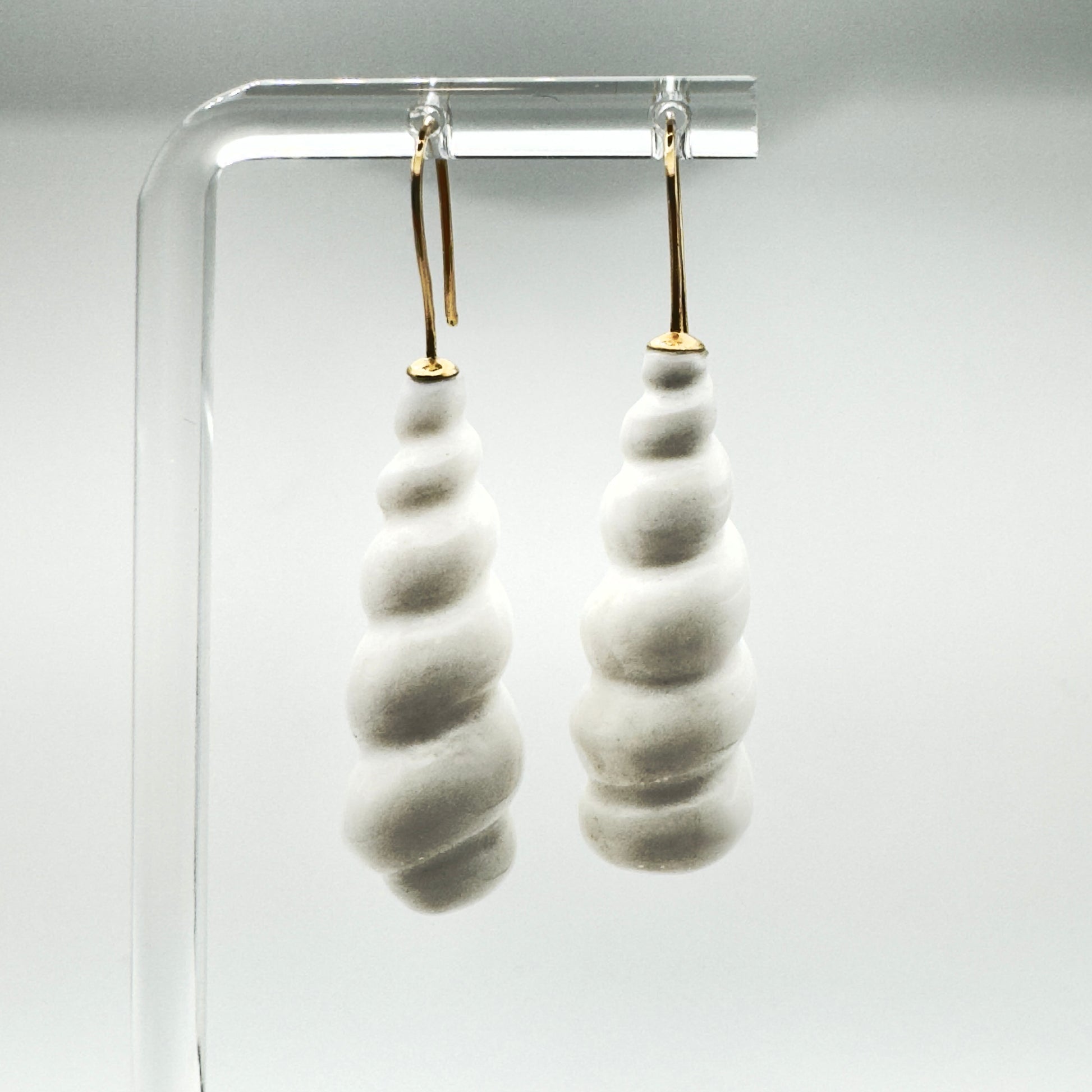Pair of white earrings hanging with white background