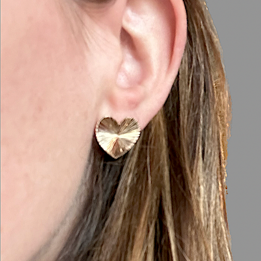 Cropped image of a woman's head with brown hair wearing a heart shaped earring