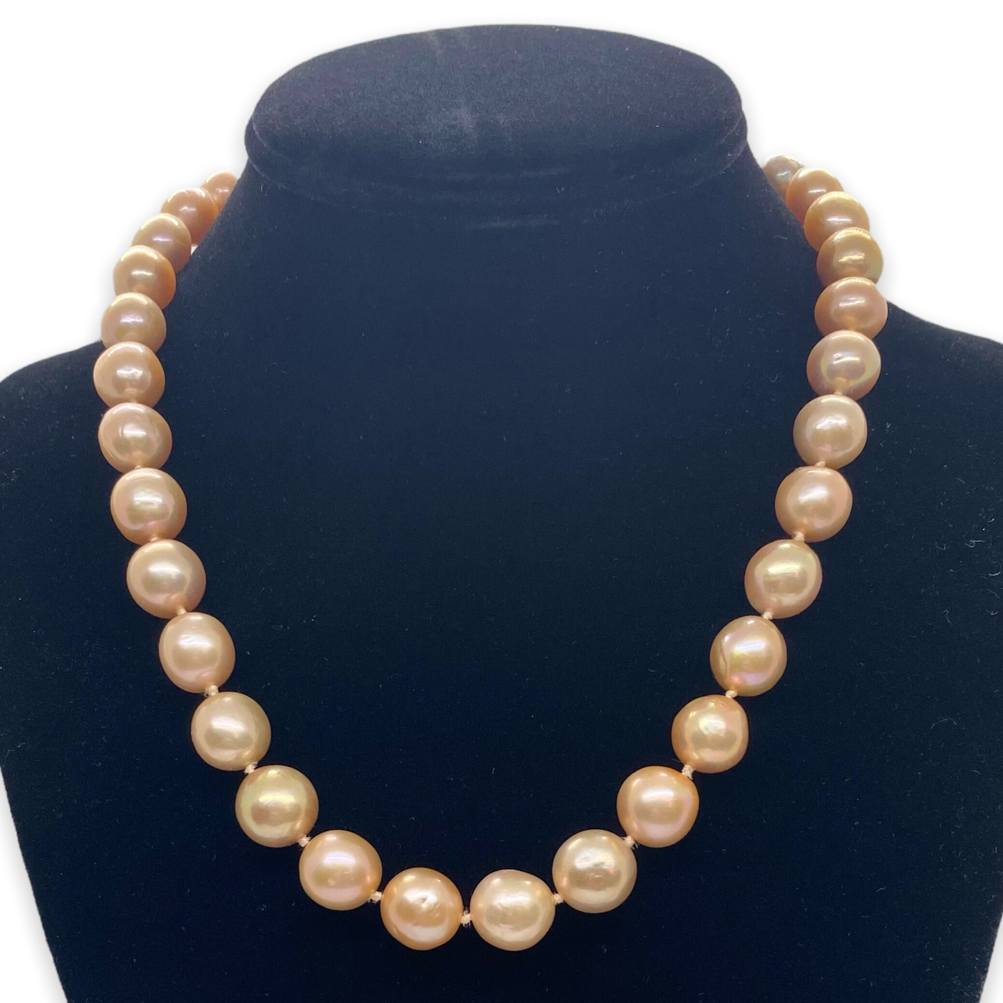 A necklace of large freshwater pink pearls displayed on a black mannequin torso.