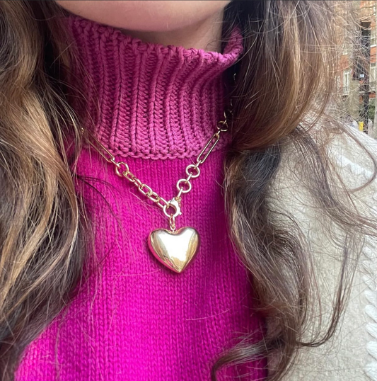 Heart shaped necklace on a person wearing a pink sweater. 