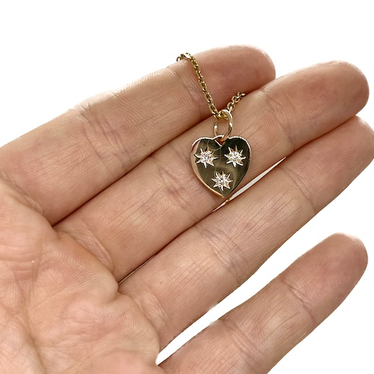 Small heart shaped pendant with diamonds held in hand. 