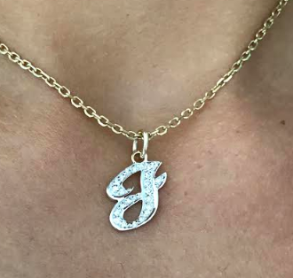 Person wearing a necklace with a pendant letter J in script. 