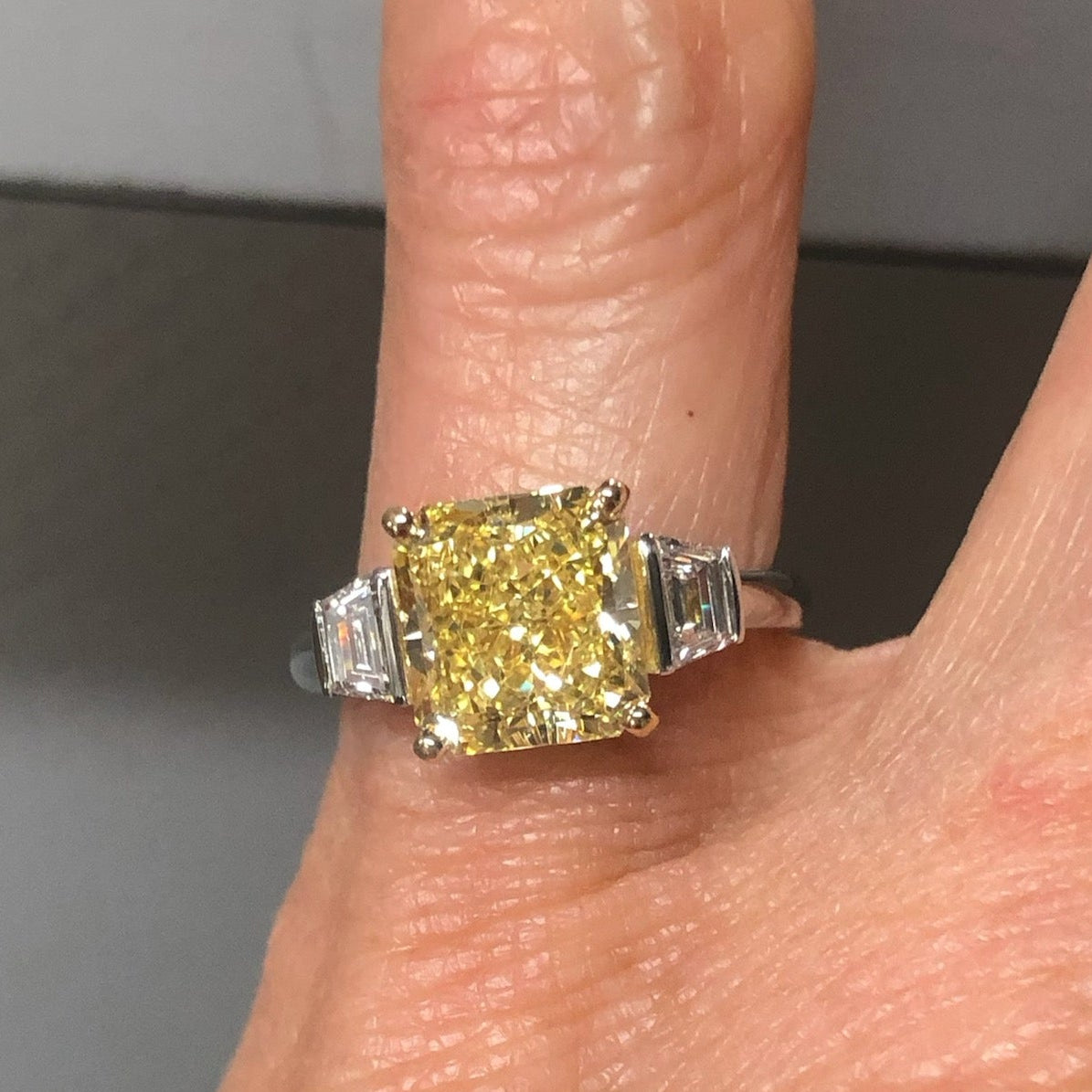 Person wearing yellow square gemstone ring.